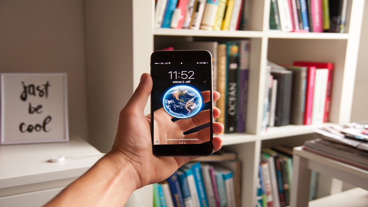 Image of smartphone with a virtual transparent screen showing a globe in a person's hand