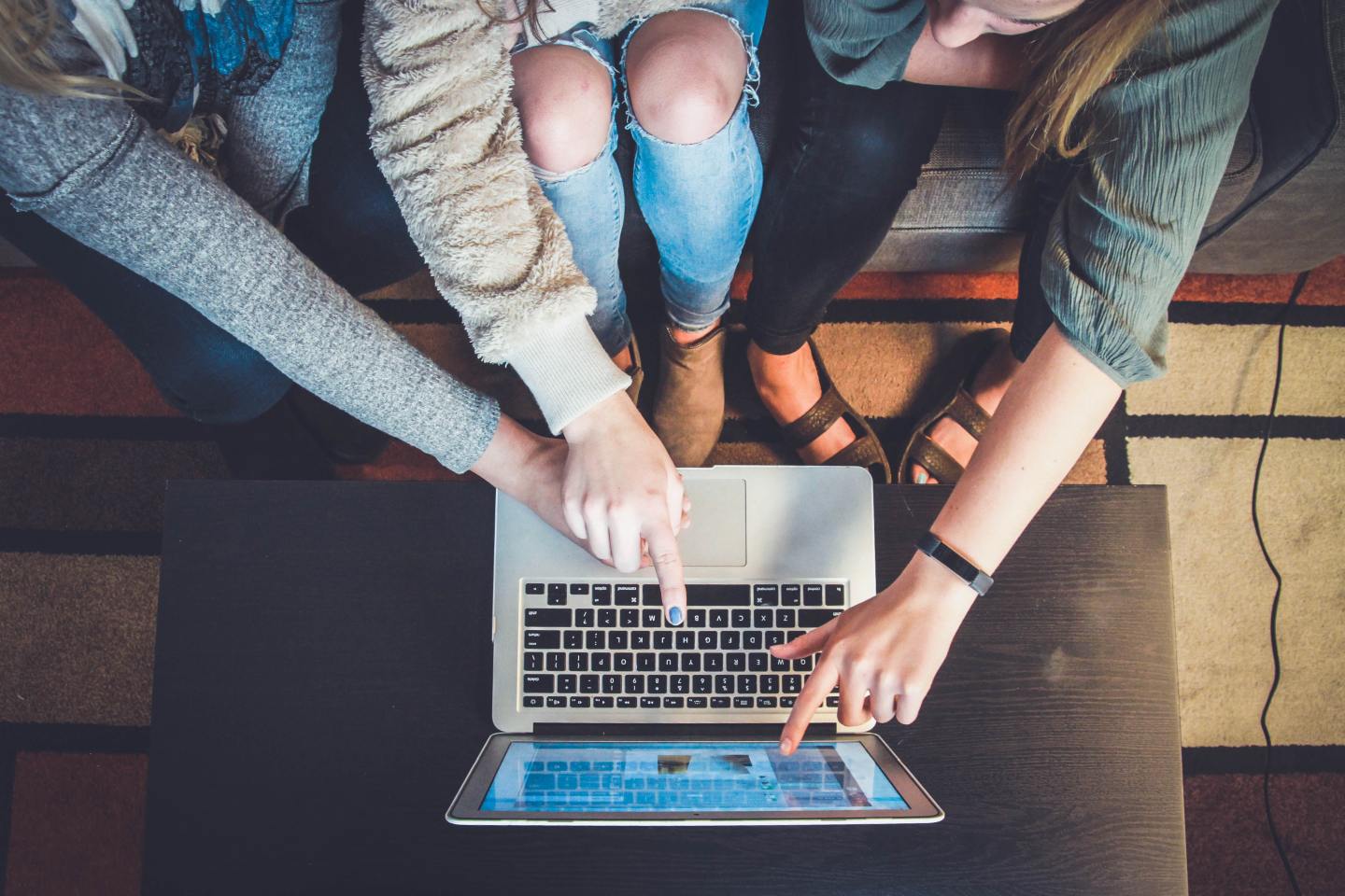 Students huddled together looking at a university website on a laptop