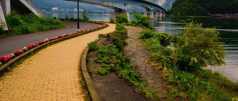 Image of a yellow brick road under a bridge and near water.