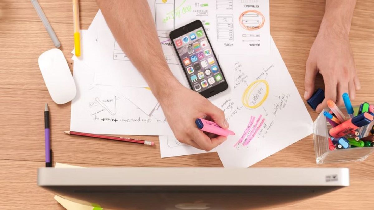 Hands drawing on paper showing workflows and wireframes for a digital system