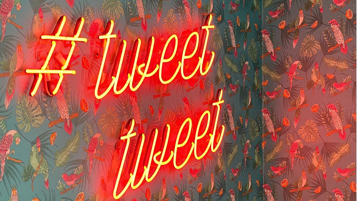 Image of a neon sign on a wall saying tweet tweet
